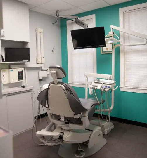 Treatment room with a dental chair and teal accent wall
