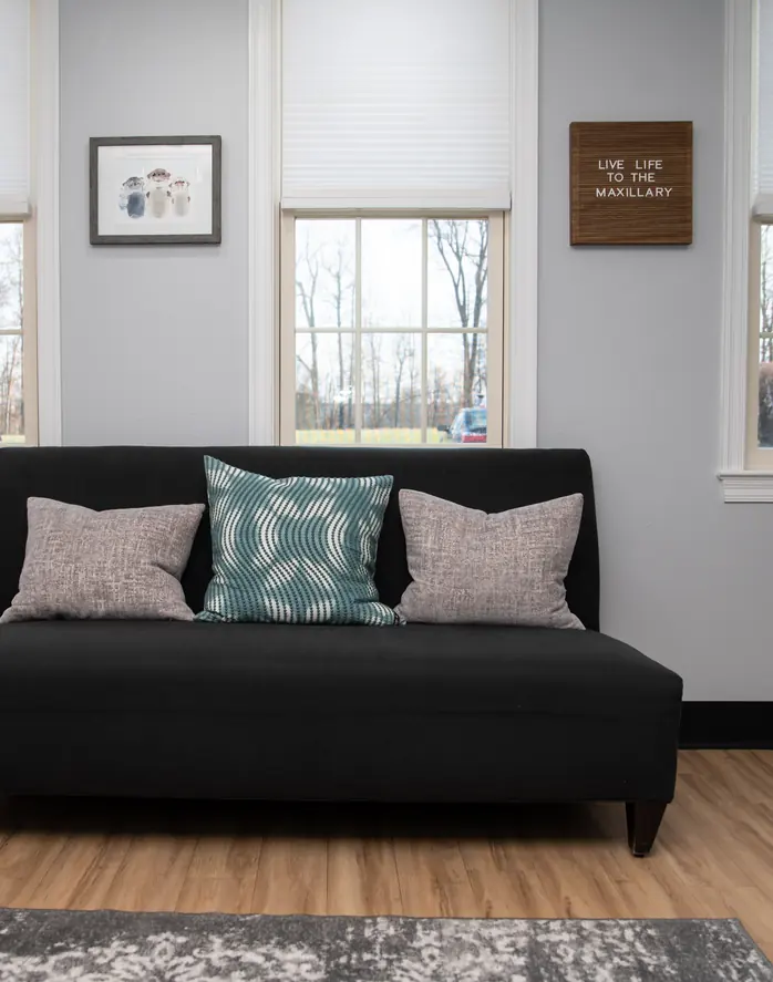 A calm waiting room with a sofa, cushions and natural light